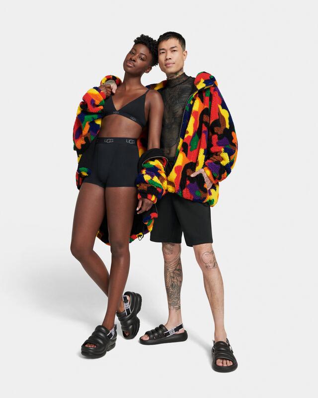 A masc person and a femme person wearing UGG sandals and Pride outerwear.